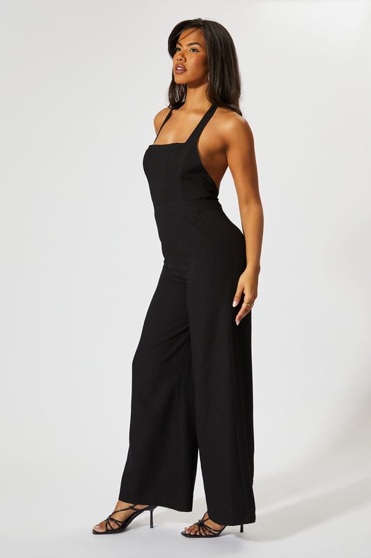 Chic halterneck design with elegant square neckline
        Straight leg silhouette for a flattering, contemporary look
        Backless feature adds a striking touch of glamour
        Wide-leg trousers create a flowing, sophisticated shape
        Linen-look fabric offers a textured finish with comfortable wear
    
    This MissPap jumpsuit combines effortless style with head-turning appeal. The halterneck design frames the dcolletage beautifully, whilst the backless detail creates a show-stopping moment when you turn around. Perfect for casual gatherings, style with strappy heels and statement earrings as seen on our model for evening drinks, or dress down with flat sandals and a woven tote for daytime events. The straight fit and wide-leg trousers create a relaxed yet polished silhouette that moves gracefully with every step. Layer with a cropped denim jacket for cooler evenings or add a waist belt to define your figure further. This versatile piece transitions seamlessly from family gatherings to sunset cocktails, making it an essential addition to your warm-weather wardrobe.
