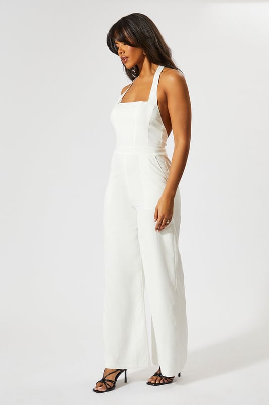 Chic halterneck design with elegant square neckline
        Straight leg silhouette for a flattering, contemporary look
        Backless feature adds a striking touch of glamour
        Wide-leg trousers create a flowing, sophisticated shape
        Linen-look fabric offers a textured finish with comfortable wear
    
    This MissPap jumpsuit combines effortless style with head-turning appeal. The halterneck design frames the dcolletage beautifully, whilst the backless detail creates a show-stopping moment when you turn around. Perfect for casual gatherings, style with strappy heels and statement earrings as seen on our model for evening drinks, or dress down with flat sandals and a woven tote for daytime events. The straight fit and wide-leg trousers create a relaxed yet polished silhouette that moves gracefully with every step. Layer with a cropped denim jacket for cooler evenings or add a waist belt to define your figure further. This versatile piece transitions seamlessly from family gatherings to sunset cocktails, making it an essential addition to your warm-weather wardrobe.