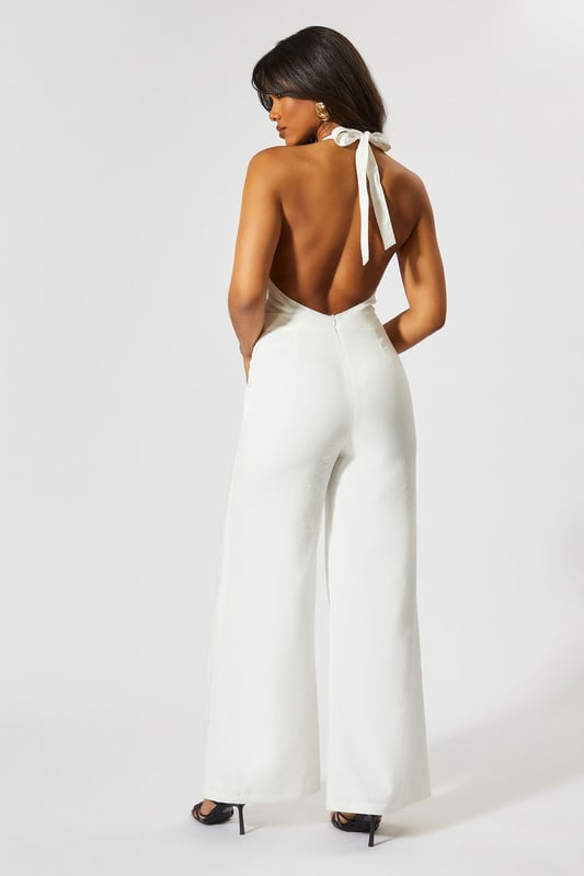 Chic halterneck design with elegant square neckline
        Straight leg silhouette for a flattering, contemporary look
        Backless feature adds a striking touch of glamour
        Wide-leg trousers create a flowing, sophisticated shape
        Linen-look fabric offers a textured finish with comfortable wear
    
    This MissPap jumpsuit combines effortless style with head-turning appeal. The halterneck design frames the dcolletage beautifully, whilst the backless detail creates a show-stopping moment when you turn around. Perfect for casual gatherings, style with strappy heels and statement earrings as seen on our model for evening drinks, or dress down with flat sandals and a woven tote for daytime events. The straight fit and wide-leg trousers create a relaxed yet polished silhouette that moves gracefully with every step. Layer with a cropped denim jacket for cooler evenings or add a waist belt to define your figure further. This versatile piece transitions seamlessly from family gatherings to sunset cocktails, making it an essential addition to your warm-weather wardrobe.