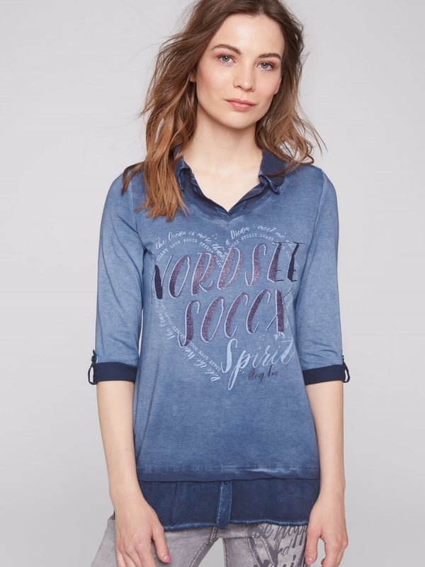Legere blouse voor dames van het merk SOCCX. De blouse-details zorgen voor een geweldig lagenlook-effect. Bij de V-hals van het jersey-shirt is een blousekraag in ton-sur-ton materiaalmix ontworpen en onderaan een geknoopt blusenschoen. Het shirt heeft sportieve 3/4-mouwen met knoopstrips voor de opgerolde stijl, een decoratieve glitterprint aan de voorkant en een kleine druk aan de achterkant. Door de speciale kleurbehandeling krijgt het damesshirt een authentieke used-look.