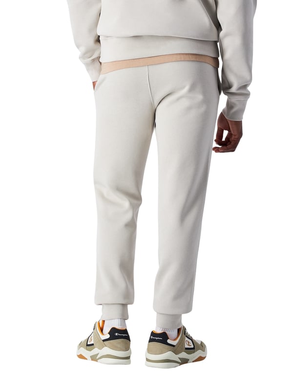Deze herenbroek van Champion verenigt stijl en functionaliteit in een perfecte herfstmetgezel. De slim fit pasvorm accentueert het figuur met een zacht gevormde silhouet, terwijl de zachte fleece-stof met een gerekte binnenkant aangename warmte biedt zonder onnodig volume toe te voegen. Voor extra comfort zorgen de elastische ribboorden, die de pasvorm optimaliseren. Twee zijzakken en een opgestikte achterzak bieden praktische opbergruimte voor onderweg. Een geborduurd C-logo-patch op de linker bovenbeen geeft een subtiele, sportieve accent en rondt het ontwerp af. Deze broek is de ideale metgezel voor koelere dagen en kan veelzijdig gecombineerd worden.