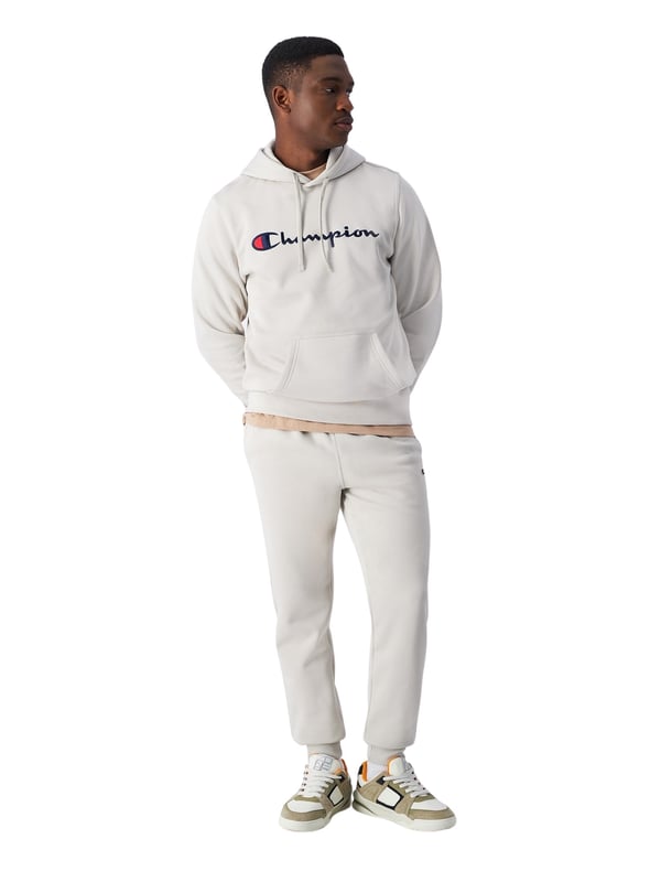 Deze herenbroek van Champion verenigt stijl en functionaliteit in een perfecte herfstmetgezel. De slim fit pasvorm accentueert het figuur met een zacht gevormde silhouet, terwijl de zachte fleece-stof met een gerekte binnenkant aangename warmte biedt zonder onnodig volume toe te voegen. Voor extra comfort zorgen de elastische ribboorden, die de pasvorm optimaliseren. Twee zijzakken en een opgestikte achterzak bieden praktische opbergruimte voor onderweg. Een geborduurd C-logo-patch op de linker bovenbeen geeft een subtiele, sportieve accent en rondt het ontwerp af. Deze broek is de ideale metgezel voor koelere dagen en kan veelzijdig gecombineerd worden.