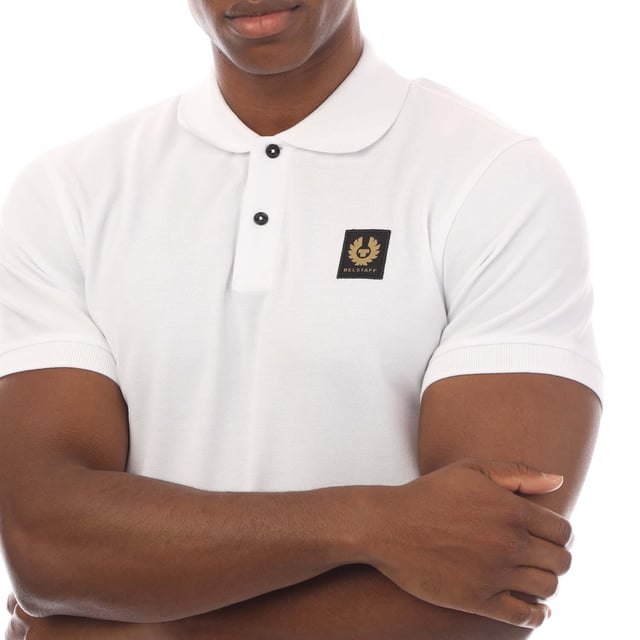 Mens Belstaff Cotton Piqué Polo Shirt in white.- Ribbed polo collar.- Two button placket.- Short sleeves with ribbed cuffs.- Embroidered Phoenix logo patch at left chest.- Uneven vented hem.- Textured cotton piqué made from organically grown cotton.- Regular fit.- Body: 100% Cotton.  Rib: 100% Cotton.  Machine washable.- Ref: 101516WHITE