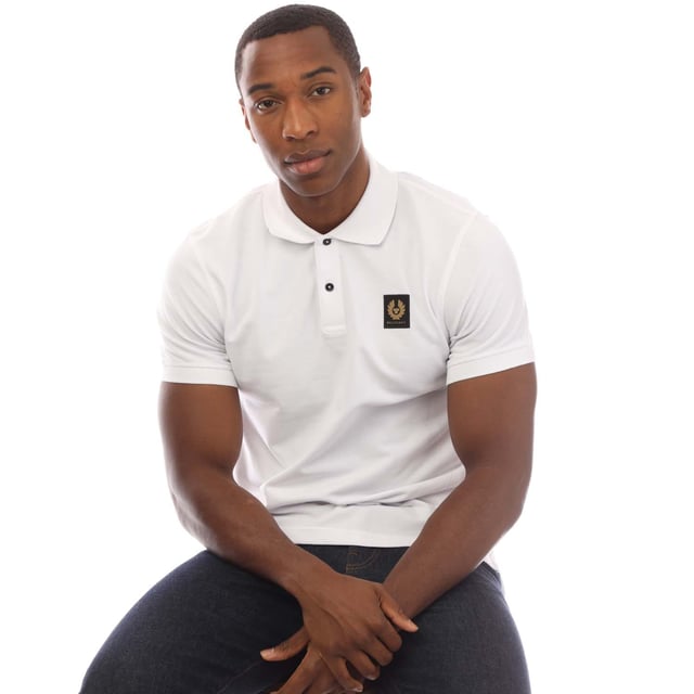 Mens Belstaff Cotton Piqué Polo Shirt in white.- Ribbed polo collar.- Two button placket.- Short sleeves with ribbed cuffs.- Embroidered Phoenix logo patch at left chest.- Uneven vented hem.- Textured cotton piqué made from organically grown cotton.- Regular fit.- Body: 100% Cotton.  Rib: 100% Cotton.  Machine washable.- Ref: 101516WHITE