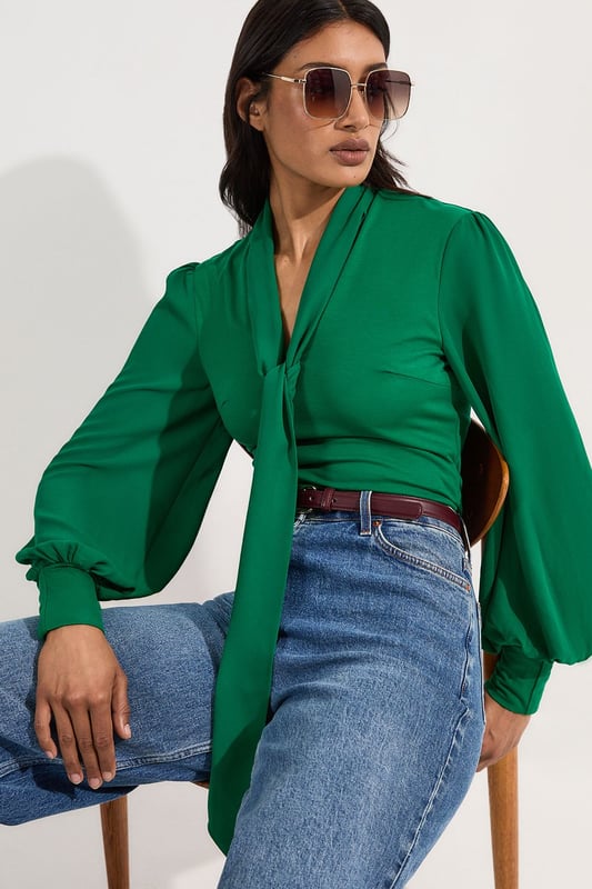 This Karen Millen bodysuit combines classic elegance with contemporary styling. The contrasting textures of jersey and georgette create visual interest, while the statement pussy bow adds a touch of feminine charm. The balloon sleeves provide dramatic volume balanced by the fitted bodice, creating a flattering silhouette. Perfect for family gatherings or casual work events, this bodysuit can be dressed down with tailored denim and flats for weekend brunches, or paired with a pencil skirt for more refined occasions. The secure bodysuit design eliminates the need for constant re-tucking, ensuring you maintain a sleek appearance throughout the day. A versatile wardrobe staple that offers both comfort and sophistication.  Jersey bodysuit featuring a georgette pussy bow detail Voluminous balloon sleeves with fitted cuffs and button detailing Round neckline Smooth, form-fitting designe