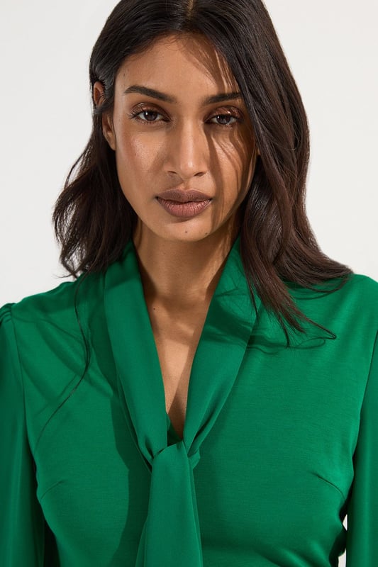This Karen Millen bodysuit combines classic elegance with contemporary styling. The contrasting textures of jersey and georgette create visual interest, while the statement pussy bow adds a touch of feminine charm. The balloon sleeves provide dramatic volume balanced by the fitted bodice, creating a flattering silhouette. Perfect for family gatherings or casual work events, this bodysuit can be dressed down with tailored denim and flats for weekend brunches, or paired with a pencil skirt for more refined occasions. The secure bodysuit design eliminates the need for constant re-tucking, ensuring you maintain a sleek appearance throughout the day. A versatile wardrobe staple that offers both comfort and sophistication.  Jersey bodysuit featuring a georgette pussy bow detail Voluminous balloon sleeves with fitted cuffs and button detailing Round neckline Smooth, form-fitting designe