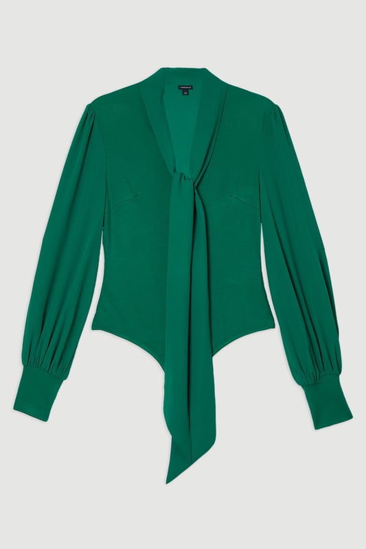 This Karen Millen bodysuit combines classic elegance with contemporary styling. The contrasting textures of jersey and georgette create visual interest, while the statement pussy bow adds a touch of feminine charm. The balloon sleeves provide dramatic volume balanced by the fitted bodice, creating a flattering silhouette. Perfect for family gatherings or casual work events, this bodysuit can be dressed down with tailored denim and flats for weekend brunches, or paired with a pencil skirt for more refined occasions. The secure bodysuit design eliminates the need for constant re-tucking, ensuring you maintain a sleek appearance throughout the day. A versatile wardrobe staple that offers both comfort and sophistication.  Jersey bodysuit featuring a georgette pussy bow detail Voluminous balloon sleeves with fitted cuffs and button detailing Round neckline Smooth, form-fitting designe