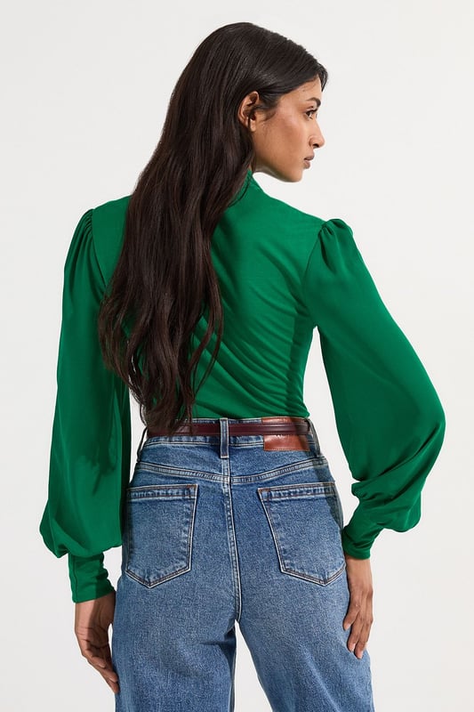 This Karen Millen bodysuit combines classic elegance with contemporary styling. The contrasting textures of jersey and georgette create visual interest, while the statement pussy bow adds a touch of feminine charm. The balloon sleeves provide dramatic volume balanced by the fitted bodice, creating a flattering silhouette. Perfect for family gatherings or casual work events, this bodysuit can be dressed down with tailored denim and flats for weekend brunches, or paired with a pencil skirt for more refined occasions. The secure bodysuit design eliminates the need for constant re-tucking, ensuring you maintain a sleek appearance throughout the day. A versatile wardrobe staple that offers both comfort and sophistication.  Jersey bodysuit featuring a georgette pussy bow detail Voluminous balloon sleeves with fitted cuffs and button detailing Round neckline Smooth, form-fitting designe