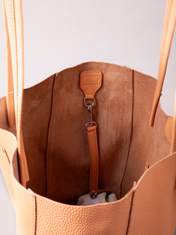 For relaxed leather luxury, look no further than the Tarn Bucket Bag in fresh apricot. This spacious tote style bag will effortlessly take you through the working week into the weekend with plenty of room for a laptop and notebooks or shopping if you&rsquo;re hitting the high street.
Crafted from real leather in a contemporary slouchy design, this bucket bag is fitted with a popper fastened top and conceals a handy inner cloth bag with zip top opening to keep your valuables extra safe. This cloth bag is securely clipped to a leather strap and is removable for ultimate versatility.