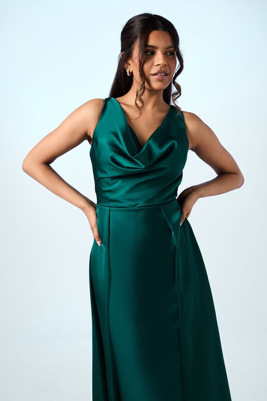 Elegant sleeveless maxi dress with a graceful cowl neckline that drapes beautifully
        Luxurious satin fabric that catches the light with subtle sheen
        Petite-friendly design with proportions tailored for shorter frames
        Flattering pleated detail that creates a flowing silhouette
        Floor-length design with a clean, sophisticated line perfect for formal occasions
    
    The Honoured Petite Bridesmaid Dress from Coast embodies timeless elegance with its fluid satin construction and graceful cowl neckline. Designed specifically for petite frames, this maxi dress offers both comfort and sophistication for your special role in the bridal party. The sleeveless cut allows for ease of movement throughout the celebration, while the pleated detailing creates a flattering shape that moves beautifully as you walk down the aisle. Complete your bridesmaid ensemble with delicate drop earrings and a simple bracelet as shown on our model, keeping accessories minimal to complement the dress's refined aesthetic. For a coordinated bridal party look, this style can be harmonised with other Coast bridesmaid dresses in matching tones, creating a cohesive and memorable wedding day aesthetic that will photograph beautifully alongside the bride.