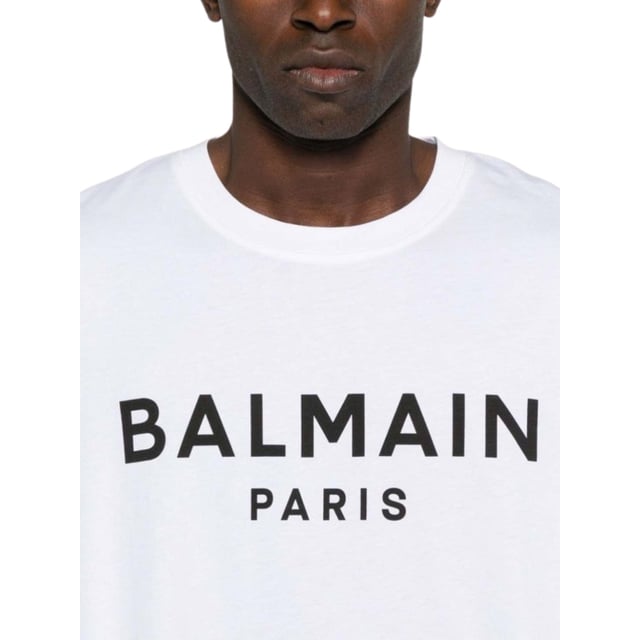 Elevate your wardrobe with the Balmain Paris Bold Brand Logo White T-Shirt, a statement piece that combines luxury and casual style effortlessly. Crafted from premium, soft cotton, this t-shirt ensures all-day comfort while showcasing the iconic Balmain logo boldly across the chest. Its crisp white colour offers versatile pairing options, making it perfect for both relaxed weekends and stylish outings. Designed for those who appreciate high fashion with a modern edge, this t-shirt adds a touch of Parisian sophistication to any outfit. Invest in timeless quality and standout style with this essential Balmain piece. 100% Cotton. Made In Italy. AH1EF000BB29 GAB