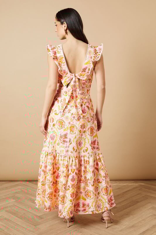 Broderie Detail V neck Midi Dress Feminine V-neckline with delicate broderie anglaise detailing
Charming flutter sleeves with ruffle trim for a playful touch
Flattering midi length with tiered hem for added movement
Defined waistband creates a beautifully structured silhouette
Striking open back design with decorative ruffle detail
This enchanting broderie detail midi dress from Oasis captures the essence of effortless daytime elegance. The intricate broderie anglaise combined with the floral pattern creates a wonderfully feminine aesthetic that's perfect for summer gatherings. Style with strappy sandals and statement earrings as seen on our model for casual brunches or garden parties. The tiered hem adds a touch of whimsy to your movement, while the defined waistband accentuates your figure beautifully. For cooler days, layer with a lightweight denim jacket and pair with white trainers for a relaxed weekend look. This versatile piece transitions seamlessly from family lunches to afternoon strolls, offering both comfort and style for your everyday wardrobe.