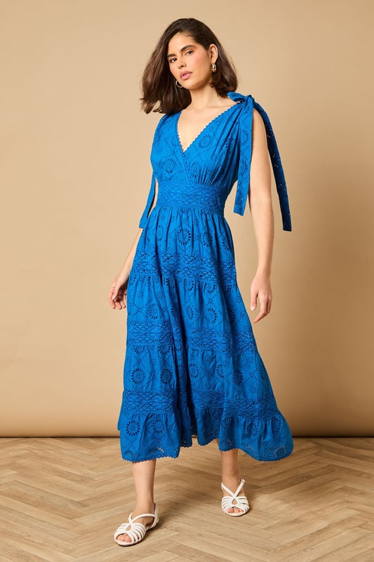 Intricate broderie anglaise detailing throughout for a feminine touch
        Flattering V-neckline at front and back for an elegant silhouette
        Charming tie shoulder straps that add a playful detail
        Tiered midi-length skirt with a relaxed, flowing shape
        Defined waistband that creates a beautifully structured fit
    
    This delightful broderie midi dress from Oasis captures effortless summer style with its feminine details and comfortable fit. The tie shoulders allow for a customised fit whilst adding a whimsical touch to the overall design. Perfect for daytime occasions, style with flat sandals as shown for a relaxed garden party or family lunch. For cooler days, layer with a lightweight denim jacket and trainers for a casual weekend look. The versatile design transitions beautifully from a countryside walk to an afternoon tea with friends. Accessorise with simple gold jewellery and a woven bag to complement the dress's intricate texture. The midi length offers both comfort and sophistication, making this a wardrobe staple that will see you through numerous casual events with ease and grace.