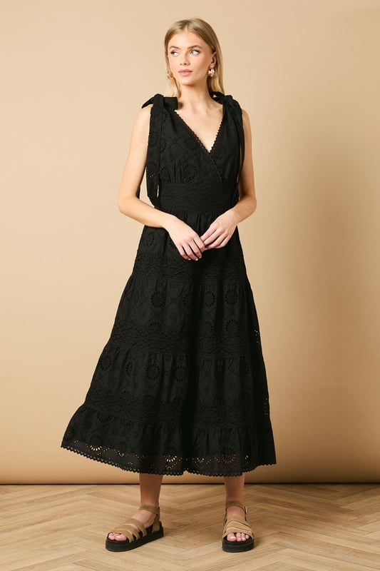 Intricate broderie anglaise detailing throughout for a feminine touch
        Flattering V-neckline at front and back for an elegant silhouette
        Charming tie shoulder straps that add a playful detail
        Tiered midi-length skirt with a relaxed, flowing shape
        Defined waistband that creates a beautifully structured fit
    
    This delightful broderie midi dress from Oasis captures effortless summer style with its feminine details and comfortable fit. The tie shoulders allow for a customised fit whilst adding a whimsical touch to the overall design. Perfect for daytime occasions, style with flat sandals as shown for a relaxed garden party or family lunch. For cooler days, layer with a lightweight denim jacket and trainers for a casual weekend look. The versatile design transitions beautifully from a countryside walk to an afternoon tea with friends. Accessorise with simple gold jewellery and a woven bag to complement the dress's intricate texture. The midi length offers both comfort and sophistication, making this a wardrobe staple that will see you through numerous casual events with ease and grace.