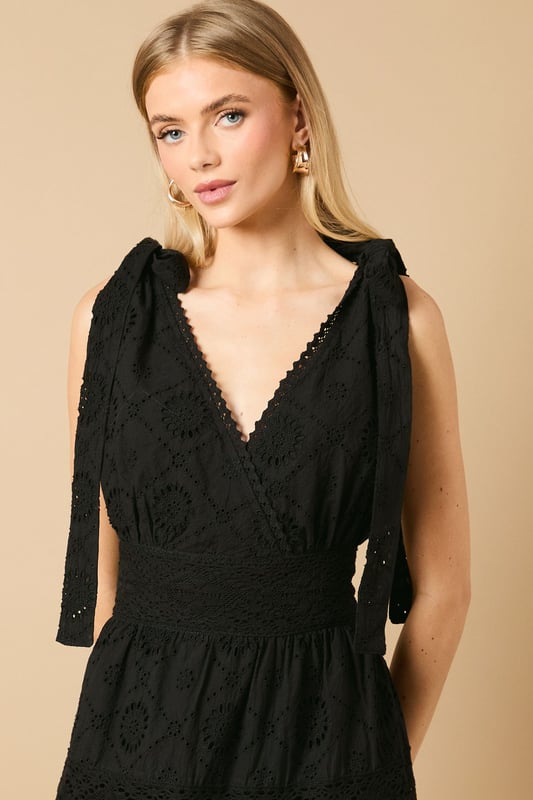 Intricate broderie anglaise detailing throughout for a feminine touch
        Flattering V-neckline at front and back for an elegant silhouette
        Charming tie shoulder straps that add a playful detail
        Tiered midi-length skirt with a relaxed, flowing shape
        Defined waistband that creates a beautifully structured fit
    
    This delightful broderie midi dress from Oasis captures effortless summer style with its feminine details and comfortable fit. The tie shoulders allow for a customised fit whilst adding a whimsical touch to the overall design. Perfect for daytime occasions, style with flat sandals as shown for a relaxed garden party or family lunch. For cooler days, layer with a lightweight denim jacket and trainers for a casual weekend look. The versatile design transitions beautifully from a countryside walk to an afternoon tea with friends. Accessorise with simple gold jewellery and a woven bag to complement the dress's intricate texture. The midi length offers both comfort and sophistication, making this a wardrobe staple that will see you through numerous casual events with ease and grace.