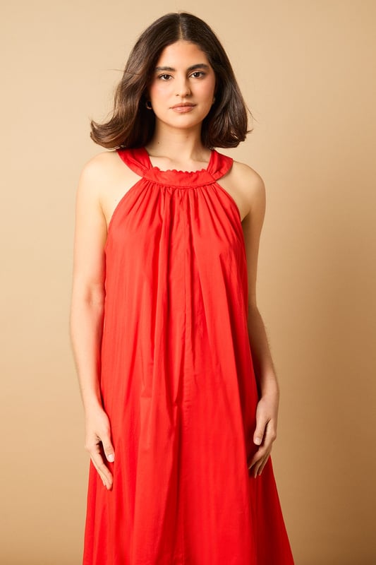Elegant halterneck design with delicate ruffle trim detail
        Flowing maxi length for graceful movement
        Relaxed smock silhouette offering effortless comfort
        Lightweight cotton voile fabric perfect for warmer days
        Tie-back fastening for an adjustable, secure fit
    
    This breezy halterneck maxi dress captures the essence of carefree summer style with its billowing smock silhouette. The soft ruffle trim around the neckline adds a touch of feminine charm, whilst the flowing fabric creates a beautifully relaxed drape that moves gracefully with every step. Style with flat sandals as seen on our model for daytime outings, or dress up with espadrille wedges and statement earrings for garden parties and alfresco dining. The versatile design makes it ideal for family gatherings, weekend brunches or holiday packing - simply throw on with a denim jacket and crossbody bag for an effortlessly chic look that transitions seamlessly from day to evening. The lightweight fabric ensures all-day comfort, whether you're strolling along the beach or enjoying a casual lunch with friends.