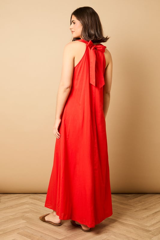 Elegant halterneck design with delicate ruffle trim detail
        Flowing maxi length for graceful movement
        Relaxed smock silhouette offering effortless comfort
        Lightweight cotton voile fabric perfect for warmer days
        Tie-back fastening for an adjustable, secure fit
    
    This breezy halterneck maxi dress captures the essence of carefree summer style with its billowing smock silhouette. The soft ruffle trim around the neckline adds a touch of feminine charm, whilst the flowing fabric creates a beautifully relaxed drape that moves gracefully with every step. Style with flat sandals as seen on our model for daytime outings, or dress up with espadrille wedges and statement earrings for garden parties and alfresco dining. The versatile design makes it ideal for family gatherings, weekend brunches or holiday packing - simply throw on with a denim jacket and crossbody bag for an effortlessly chic look that transitions seamlessly from day to evening. The lightweight fabric ensures all-day comfort, whether you're strolling along the beach or enjoying a casual lunch with friends.