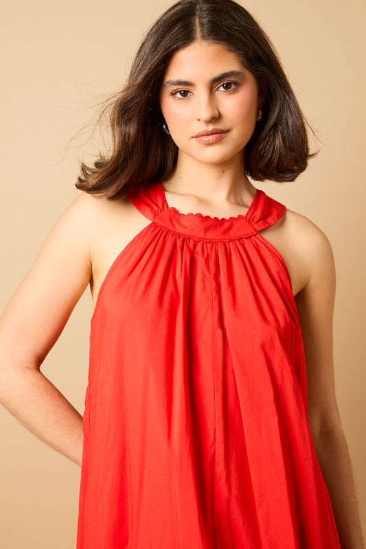 Elegant halterneck design with delicate ruffle trim detail
        Flowing maxi length for graceful movement
        Relaxed smock silhouette offering effortless comfort
        Lightweight cotton voile fabric perfect for warmer days
        Tie-back fastening for an adjustable, secure fit
    
    This breezy halterneck maxi dress captures the essence of carefree summer style with its billowing smock silhouette. The soft ruffle trim around the neckline adds a touch of feminine charm, whilst the flowing fabric creates a beautifully relaxed drape that moves gracefully with every step. Style with flat sandals as seen on our model for daytime outings, or dress up with espadrille wedges and statement earrings for garden parties and alfresco dining. The versatile design makes it ideal for family gatherings, weekend brunches or holiday packing - simply throw on with a denim jacket and crossbody bag for an effortlessly chic look that transitions seamlessly from day to evening. The lightweight fabric ensures all-day comfort, whether you're strolling along the beach or enjoying a casual lunch with friends.