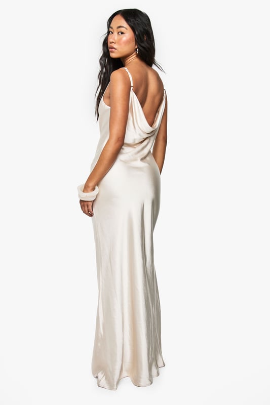 Elegant satin maxi dress with a stunning cowl neckline that drapes beautifully
        Figure-flattering silhouette with a sleek, floor-length design
        Adjustable spaghetti straps for a customised fit
        Dramatic cowl back detail adds a touch of sophistication
        Smooth, flowing fabric that glides gracefully with movement
    
    Make a striking impression at your next formal occasion with this Boohoo bridesmaid satin maxi dress. The luxurious fabric catches the light beautifully as you move, whilst the cowl neckline frames your dcolletage with effortless elegance. Style with delicate jewellery and a small clutch bag, as shown on our model, to maintain the dress's refined silhouette. Perfect for weddings, formal dinners, and black-tie events, this gown offers timeless appeal that photographs beautifully. The draped back detail adds unexpected drama when you turn, ensuring you look just as captivating from every angle. For cooler evenings, pair with a lightweight pashmina or tailored jacket to complete your sophisticated ensemble.