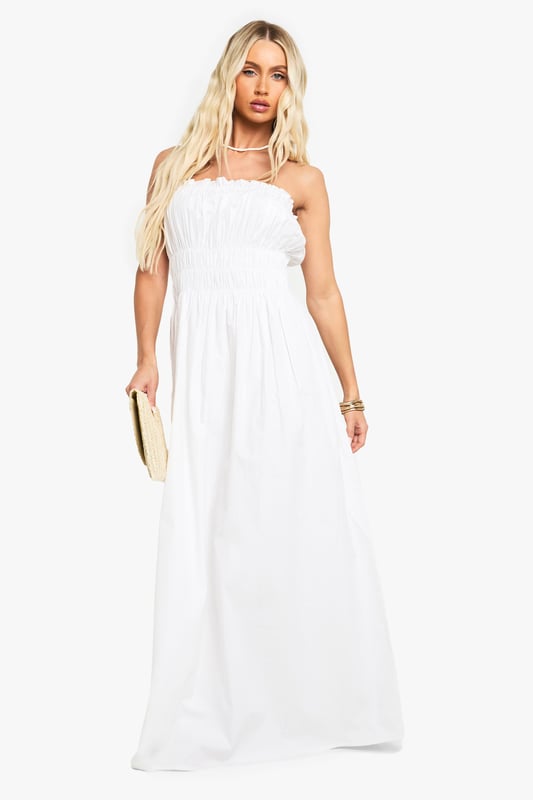 Elegant bandeau neckline with delicate ruched detailing across the bodice
        Lightweight cotton poplin fabric offers breathable comfort for all-day wear
        Floor-sweeping maxi length creates a graceful silhouette
        Elasticated shirred upper section ensures a comfortable, secure fit
        Flowing skirt design provides effortless movement and versatility
    
    This stunning cotton maxi dress showcases beautiful ruched detailing that creates a flattering silhouette whilst maintaining day-long comfort. The strapless bandeau design presents the perfect canvas for showcasing your favourite jewellery, as demonstrated by the model's choice of layered necklaces. Style with flat sandals and a woven clutch for casual garden parties or family gatherings. For a more refined daytime look, add a cropped denim jacket and delicate bangles. The dress's relaxed fit makes it ideal for warm-weather holidays - simply throw on with oversized sunglasses and a wide-brimmed hat for instant beachside sophistication. The versatile design transitions seamlessly from day to evening, making it a must-have addition to your summer wardrobe.