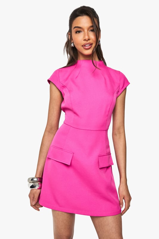 Structured woven fabric with textured finish for added dimension
        High neckline with cap sleeves for a sophisticated silhouette
        Figure-defining fitted waist that accentuates your shape
        Decorative pocket details at the hips for a modern twist
        Mini length perfect for showcasing your legs
    
    Make a statement in this head-turning mini dress from Boohoo. The high neckline and structured silhouette create a contemporary look that commands attention, whilst the textured fabric adds visual interest to this standout piece. Style with strappy heels and stacked bangles as seen on our model for a night out with the girls, or dress it down with white trainers and a denim jacket for daytime drinks. The versatile design works brilliantly for everything from cocktails at a trendy bar to birthday celebrations. The pocket details add a functional yet fashionable element to this already striking dress. Complete your look with a sleek ponytail and statement earrings to truly showcase this bold, party-ready number.