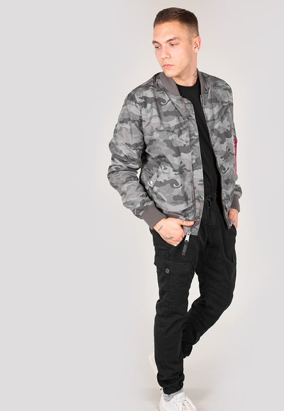 La chaqueta bomber MA-1 TT Two Tone Camo de Alpha Industries combina el estilo clásico de una bomber con un diseño moderno de camuflaje. El corte slim realza la silueta, mientras que el resistente material de nailon es ligero y resistente a la intemperie. Cuenta con bolsillos exteriores, un bolsillo interior y un bolsillo utilitario en la manga con etiqueta RBF, además de puños de canalé que protegen contra el viento. El forro interior naranja y la etiqueta con bandera en la manga refuerzan el icónico estilo Alpha. Ideal para combinar con vaqueros y sudaderas para un look moderno.
