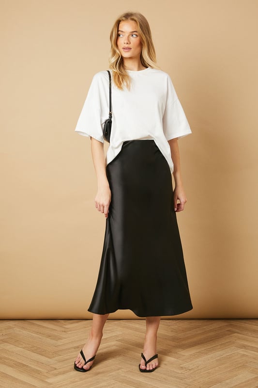 Elegant bias cut design creates a flattering drape that skims the silhouette
        Lustrous satin finish catches the light beautifully as you move
        Mid-calf length offers versatile styling options for various occasions
        Smooth waistband sits comfortably at the natural waist
        Fluid A-line shape provides effortless movement throughout the day
    
    This Oasis bias cut midi skirt brings timeless sophistication to your everyday wardrobe. The diagonal cutting technique creates a gorgeous drape that flows with your body, whilst the satin finish adds a subtle touch of luxury to casual ensembles. Style as seen with a relaxed oversized tee and minimal flip-flop sandals for an effortlessly chic daytime look. For family gatherings or brunches with friends, pair with a fitted knit top and ballet flats. The versatile midi length works beautifully with trainers for a contemporary twist, or dress it up with block-heeled mules for dinner dates. This skirt transitions seamlessly from weekend shopping trips to casual office settings when paired with a crisp button-down and loafers. A true wardrobe essential that combines feminine charm with practical wearability.