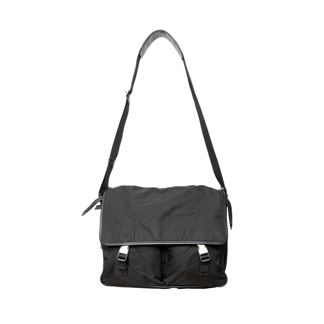 VINTAGE, RRP AS NEW
This black re-nylon messenger bag with trim features dual buckle closures on pockets, a side lock, and an enamel triangle signature brand emblem for a sleek finish.
Inclusion: dust bag
Remarks: there are some signs of wear on the hardware. Measurments:  width: 965 mm height: 812 mm
