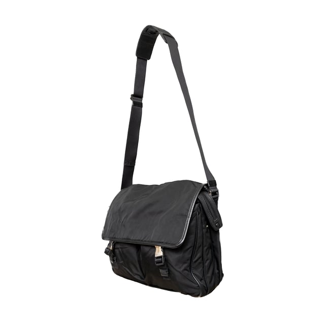 VINTAGE, RRP AS NEW
This black re-nylon messenger bag with trim features dual buckle closures on pockets, a side lock, and an enamel triangle signature brand emblem for a sleek finish.
Inclusion: dust bag
Remarks: there are some signs of wear on the hardware. Measurments:  width: 965 mm height: 812 mm