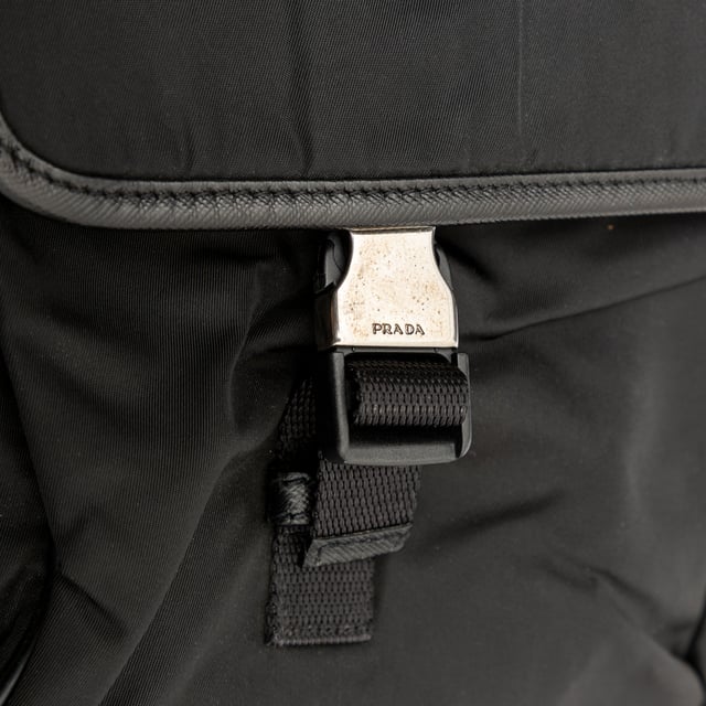 VINTAGE, RRP AS NEW
This black re-nylon messenger bag with trim features dual buckle closures on pockets, a side lock, and an enamel triangle signature brand emblem for a sleek finish.
Inclusion: dust bag
Remarks: there are some signs of wear on the hardware. Measurments:  width: 965 mm height: 812 mm