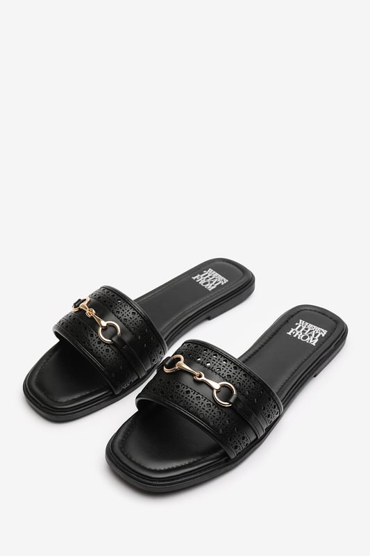 Wheres That From Womens 'Natalie' Sliders With Geometric Strap And Metal Detail Step into timeless elegance with these Natalie Sliders With Geometric Strap And Metal Detail. Designed with a chic metallic horse-bit buckle, they effortlessly blend sophistication and comfort. The perforated upper adds breathable style, while the slip-on design makes them ideal for effortless wear from day to night. Perfect for holidays, casual brunches, or a polished everyday look. Key Features: • Material: Faux leather upper with a cushioned insole for all-day comfort • Design: Perforated detailing with a stylish horse-bit buckle accent • Closure: Easy slip-on style for convenience