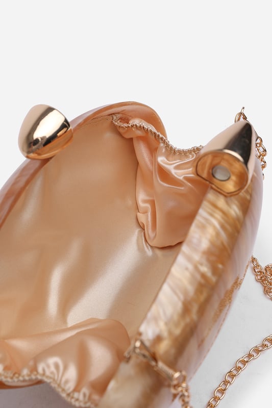Make a statement with the ocean-inspired Benna Marble Acrylic Clutch In Gold, designed to turn heads at any special event. Its sculpted silhouette and glossy marbled finish evoke luxurious, artistic charm. Finished with a sleek gold-tone clasp, this compact clutch carries your essentials in standout style. Key Features: • Material: High-gloss marbled acrylic • Dimensions: Approximately 19cm (L) x 11cm (H) x 5cm (W) • Fastening: Gold-tone twist clasp closure • Detail: Unique curved design with swirling marble effect for a luxe finish