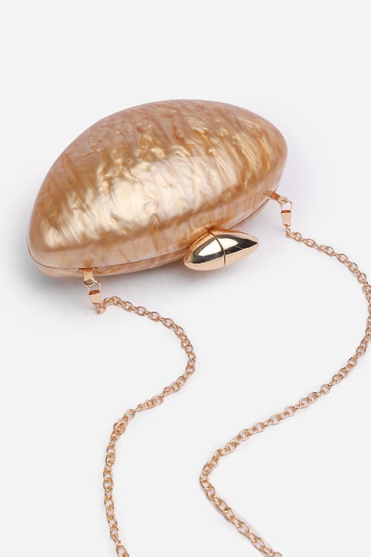 Make a statement with the ocean-inspired Benna Marble Acrylic Clutch In Gold, designed to turn heads at any special event. Its sculpted silhouette and glossy marbled finish evoke luxurious, artistic charm. Finished with a sleek gold-tone clasp, this compact clutch carries your essentials in standout style. Key Features: • Material: High-gloss marbled acrylic • Dimensions: Approximately 19cm (L) x 11cm (H) x 5cm (W) • Fastening: Gold-tone twist clasp closure • Detail: Unique curved design with swirling marble effect for a luxe finish