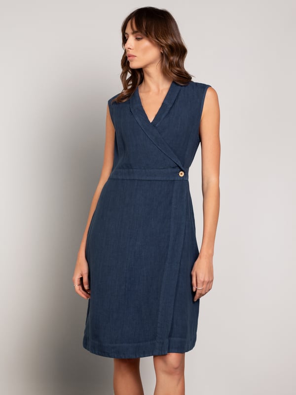 This wrap dress features a shawl collar neckline with adjustable self-ties at the back for a custom fit. Knee-length and sleeveless with practical side-seam pockets, it combines easy style with versatility.