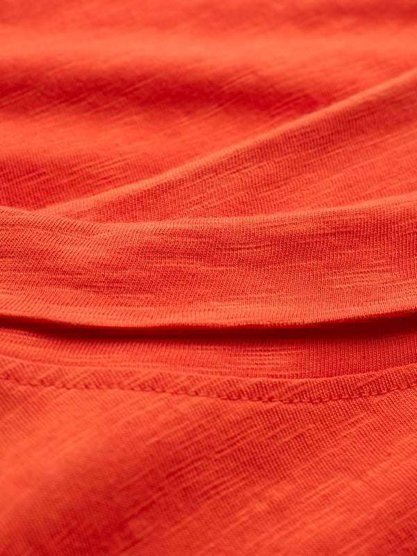 This knee-length dress offers a relaxed, straight fit with a folded boat collar and grown-on sleeves. The slub jersey fabric adds subtle texture, while practical side seam pockets provide versatility for everyday wear.