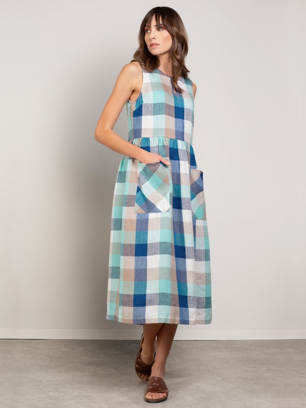 This sleeveless midi dress is made from a mid-weight, woven fabric. The large scale gingham print is bright and summery. The skirt is gathered at the waist seam to provide a full, drapey appearance, and has large patch pockets that are cut on the bias, adding nice detail. The crew neckline features a keyhole detail with two coconut buttons and loop fastenings.