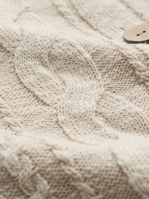 This cardigan has a classic cable-knit pattern with a relaxed, drop-shoulder shape, finished with natural coconut buttons. The cotton-linen blend lends an airy feel, while the crew neckline and boxy fit create an easy, everyday layer.