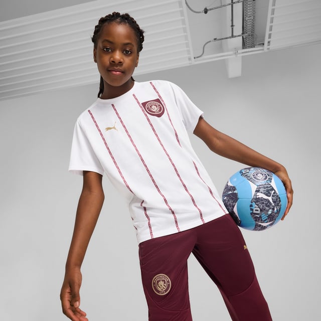 PUMA Kids Unisex Manchester City Pre-match Jersey PRODUCT STORY: Show your love for Manchester's best club with this PUMA jersey. Featuring iconic team branding, high-performance details, and sleek PUMA details, it's perfect for cheering at the Etihad Stadium or repping your team wherever you go. Feel the energy, wear the pride. FEATURES & BENEFITS: dryCELL: Performance technology designed to wick moisture from the body and keep you free of sweat during exercise; Made with 100% recycled material excluding trims & decorations. DETAILS: Regular fit; Single jersey material; Regular length; Crew neck; Short sleeves; Medium rise; Printed graphic; Manchester City badge and PUMA Cat logo; PUMA Youth: Recommended for older kids between 8 and 16 years.