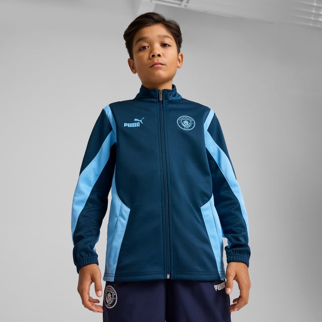 PRODUCT STORY: Young Cityzens, express your pride with this PUMA jacket featuring a multi-layered Man City silicone badge, flatlock stitching, and a PUMA Cat logo on the chest. The elasticated waistband and cuffs ensure a snug fit. Feel the Etihad Stadium energy and represent the Sky Blues with every step you take. DETAILS: Regular fit; Spacer material; Flatlock stitching; Hood; Full zip; Long sleeves; Elasticated waistband and cuffs; Multi-layered Manchester City silicone badge; PUMA Cat logo on the chest; PUMA Youth: Recommended for older kids between 8 and 16 years.