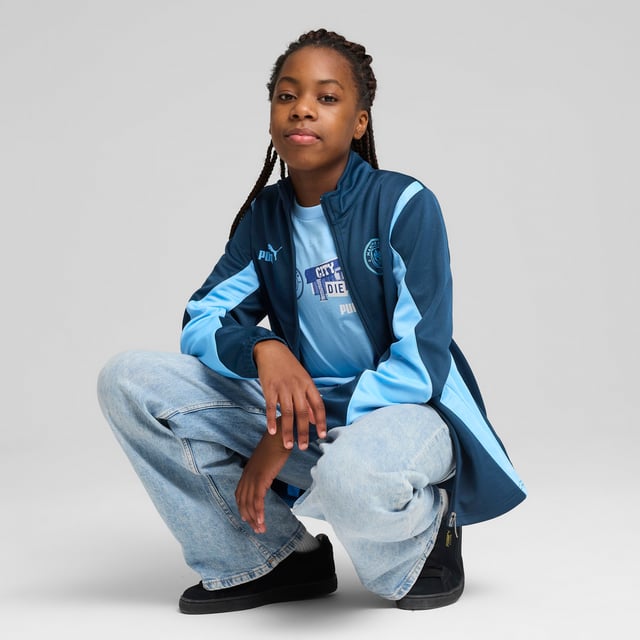 PRODUCT STORY: Young Cityzens, express your pride with this PUMA jacket featuring a multi-layered Man City silicone badge, flatlock stitching, and a PUMA Cat logo on the chest. The elasticated waistband and cuffs ensure a snug fit. Feel the Etihad Stadium energy and represent the Sky Blues with every step you take. DETAILS: Regular fit; Spacer material; Flatlock stitching; Hood; Full zip; Long sleeves; Elasticated waistband and cuffs; Multi-layered Manchester City silicone badge; PUMA Cat logo on the chest; PUMA Youth: Recommended for older kids between 8 and 16 years.