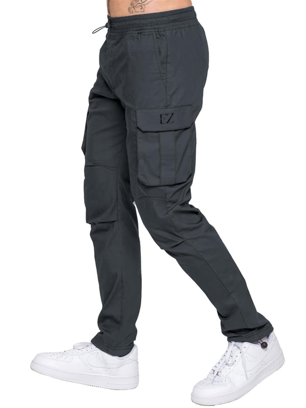 Upgrade your everyday style with the Enzo Men's Cargo Pants. Crafted from premium stretch fabric, these lightweight trousers offer a tapered leg fit for a sleek, modern look. Featuring an elasticated waistband with an adjustable toggle, they provide a customizable fit, while the adjustable toggle ankles let you tailor the look and feel. With two side slash pockets, two cargo pockets with secure Velcro fastening, and a single back welt pocket, you’ll have ample storage for essentials. Finished with an Enzo print on the cargo pocket. (649)