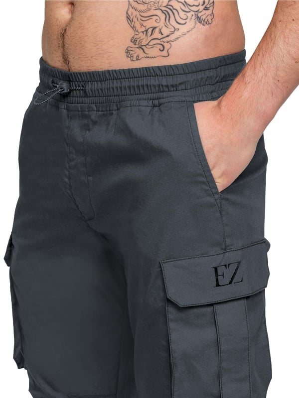 Upgrade your everyday style with the Enzo Men's Cargo Pants. Crafted from premium stretch fabric, these lightweight trousers offer a tapered leg fit for a sleek, modern look. Featuring an elasticated waistband with an adjustable toggle, they provide a customizable fit, while the adjustable toggle ankles let you tailor the look and feel. With two side slash pockets, two cargo pockets with secure Velcro fastening, and a single back welt pocket, you’ll have ample storage for essentials. Finished with an Enzo print on the cargo pocket. (649)