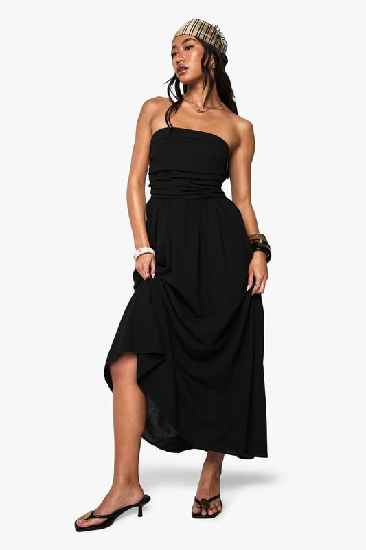 Chic bandeau neckline with a single shoulder strap for added support
        Flattering gathered waistband that defines your silhouette
        Flowing midi-length skirt with elegant side slit for ease of movement
        Lightweight linen-look fabric perfect for warm-weather occasions
        Versatile design that can be dressed up or down for various events
    
    This bandeau midi dress combines effortless style with practical comfort for your casual wardrobe. The striking asymmetric strap detail adds a contemporary twist to the classic bandeau design, while the gathered waistband creates a flattering shape that complements all figures. Style with flat sandals and a beanie for a relaxed daytime look, as shown by our model, or swap for kitten heels and statement jewellery for family gatherings. The side slit offers both practical movement and a subtle flash of leg, making this dress ideal for garden parties or brunches with friends. Layer with a denim jacket when the temperature drops or add a crossbody bag to keep your essentials close while maintaining the dress's clean lines. This Boohoo staple will quickly become your go-to for those "nothing to wear" moments.