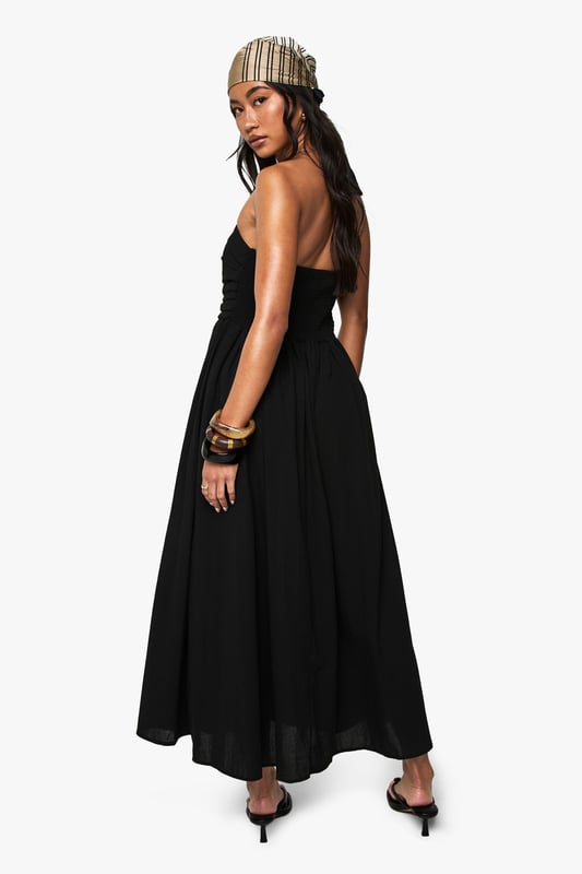 Chic bandeau neckline with a single shoulder strap for added support
        Flattering gathered waistband that defines your silhouette
        Flowing midi-length skirt with elegant side slit for ease of movement
        Lightweight linen-look fabric perfect for warm-weather occasions
        Versatile design that can be dressed up or down for various events
    
    This bandeau midi dress combines effortless style with practical comfort for your casual wardrobe. The striking asymmetric strap detail adds a contemporary twist to the classic bandeau design, while the gathered waistband creates a flattering shape that complements all figures. Style with flat sandals and a beanie for a relaxed daytime look, as shown by our model, or swap for kitten heels and statement jewellery for family gatherings. The side slit offers both practical movement and a subtle flash of leg, making this dress ideal for garden parties or brunches with friends. Layer with a denim jacket when the temperature drops or add a crossbody bag to keep your essentials close while maintaining the dress's clean lines. This Boohoo staple will quickly become your go-to for those "nothing to wear" moments.