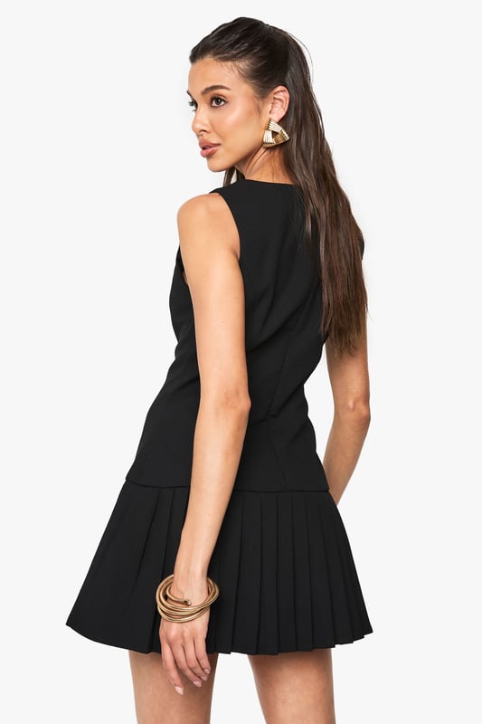 Sleeveless mini dress with elegant slash neckline for a sophisticated silhouette
        Decorative button detail running down the front adds a chic, structured element
        Pleated skirt creates playful movement and a flattering flare
        Fitted waist design accentuates your natural shape
        Versatile crepe fabric offers comfortable stretch whilst maintaining structure
    
    This striking mini dress from Boohoo combines classic tailoring with contemporary flair. The fitted bodice with its distinctive button detailing creates a polished look, while the pleated skirt adds a touch of playfulness perfect for evening adventures. Style with strappy heels and statement earrings as shown for a night at the club, or dress down with chunky trainers and an oversized denim jacket for casual drinks with friends. The versatile design transitions effortlessly from day to night - pair with a tailored blazer for impromptu after-work gatherings or showcase on its own with a mini handbag for those spontaneous nights out. The structured yet comfortable fit makes this dress a reliable go-to when you want to make an impression whilst feeling confident on the dance floor.
