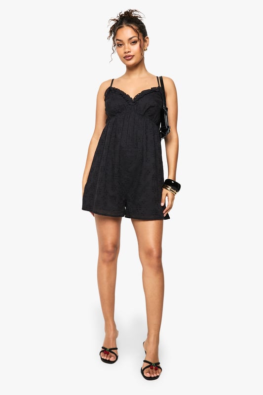 Crafted from delicate broderie anglaise fabric with intricate eyelet detailing
        Feminine V-neckline with scalloped trim for a romantic touch
        Adjustable spaghetti straps for a customised fit
        Relaxed silhouette with a flattering empire waistline
        Lightweight design perfect for warm-weather occasions
    
    This charming broderie anglaise playsuit from Boohoo combines comfort with effortless style. The delicate eyelet pattern and scalloped trim create a feminine aesthetic that works beautifully for daytime events. Style with flat sandals and stacked bangles as shown for casual gatherings, or dress up with espadrille wedges and a woven clutch for garden parties. The relaxed fit makes it ideal for family barbecues or weekend brunches, while the all-in-one design offers practicality without compromising on style. For cooler evenings, layer with a lightweight denim jacket and switch to ankle boots for versatility that transitions through the seasons. This playsuit embodies carefree summer dressing with its easy-to-wear appeal and timeless broderie fabric.