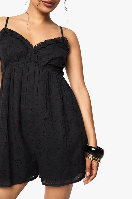 Crafted from delicate broderie anglaise fabric with intricate eyelet detailing
        Feminine V-neckline with scalloped trim for a romantic touch
        Adjustable spaghetti straps for a customised fit
        Relaxed silhouette with a flattering empire waistline
        Lightweight design perfect for warm-weather occasions
    
    This charming broderie anglaise playsuit from Boohoo combines comfort with effortless style. The delicate eyelet pattern and scalloped trim create a feminine aesthetic that works beautifully for daytime events. Style with flat sandals and stacked bangles as shown for casual gatherings, or dress up with espadrille wedges and a woven clutch for garden parties. The relaxed fit makes it ideal for family barbecues or weekend brunches, while the all-in-one design offers practicality without compromising on style. For cooler evenings, layer with a lightweight denim jacket and switch to ankle boots for versatility that transitions through the seasons. This playsuit embodies carefree summer dressing with its easy-to-wear appeal and timeless broderie fabric.