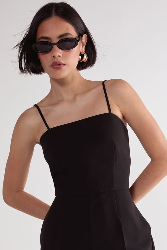 Sleek capri-length playsuit with tailored fit for a flattering silhouette
        Elegant square neckline with delicate adjustable spaghetti straps
        Practical side pockets for convenient storage of small essentials
        Cropped leg design offers a modern, sophisticated twist on classic playsuit styling
        Structured woven fabric provides comfortable stretch while maintaining shape
    
    This versatile Nasty Gal playsuit combines timeless tailoring with contemporary design for effortless style. The structured capri-length creates a refined silhouette that works beautifully for casual daytime events. Style with strappy kitten heels and statement earrings as seen on our model for family gatherings, or dress down with trendy trainers and an oversized tote for weekend brunches. The clean lines and minimalist design make this piece particularly adaptable for transitional weather-simply layer with a lightweight cardigan or cropped jacket when temperatures drop. The tailored fit flatters the waistline while the practical pockets add functionality to this chic wardrobe staple. Perfect for those seeking a balance of comfort and style for various casual occasions.