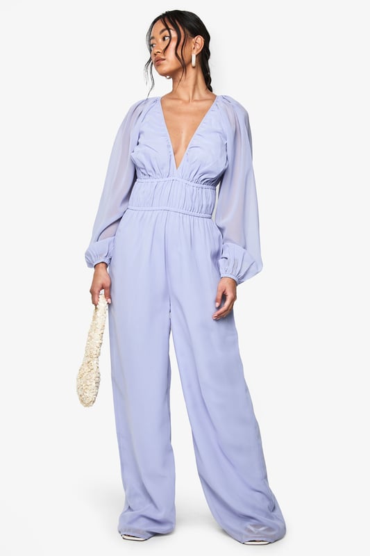 Elegant chiffon jumpsuit featuring a plunging V-neckline for a striking silhouette
        Ruched waistband detail creates a flattering, defined waist
        Dramatic wide-leg design offers comfortable movement and a fashion-forward look
        Billowing long sleeves with gathered cuffs add romantic flair
        Flowing fabric drapes beautifully for an effortlessly chic appearance
    
    Make a statement at your next night out in this show-stopping wide-leg jumpsuit. The plunging V-neckline creates an alluring focal point, whilst the ruched waistband cinches you in at just the right spot for a figure-enhancing effect. The billowing sleeves and flowing wide legs create a beautifully balanced silhouette that moves gracefully as you do. Style with strappy heels and a woven clutch, as shown, for drinks with the girls, or dress it up with statement earrings and metallic accessories for special occasions. This versatile Boohoo piece transitions seamlessly from cocktail bars to dance floors, ensuring you'll stand out for all the right reasons. Perfect for those who want to combine comfort with head-turning style for their evening adventures.