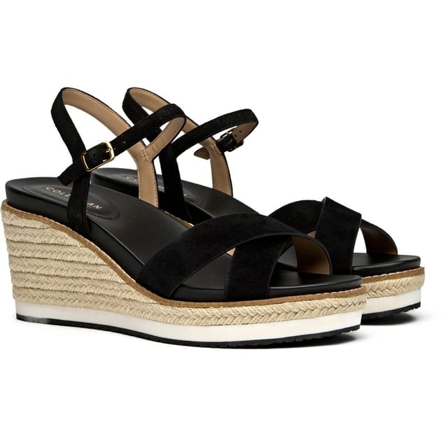 Cole Haan Silvee Sandals The Cole Haan Silvee brings sophisticated elevation to warm-weather dressing with its luxurious nubuck upper and distinctive rope-edged sole. This black espadrille sandal features a secure buckle closure and generous 9cm heel that adds statuesque height while maintaining comfort through its cushioned insole. The rubber and rope sole construction delivers both style and durability, making it perfect for everything from weekend brunches to evening gatherings.